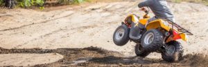 Person riding a all-terrain vehicle (ATV) through mud