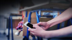 Student checks their phone secretly under a desk in a classroom